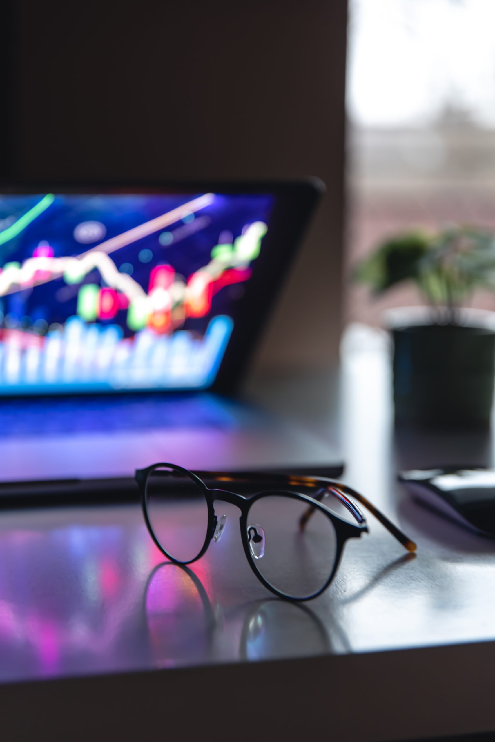 Laptop with graphs and statistics and glasses on the table.